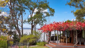 Une terrasse en bois, aménagée avec du mobilier d’extérieur, donnant sur un lac.