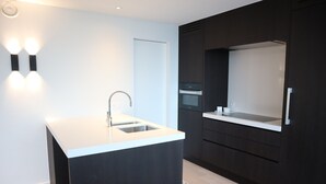 A modern kitchen with a central island, dark cabinetry, and built-in appliances.
