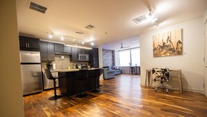A modern kitchen with dark cabinets, a stainless steel refrigerator, and a bar area with stools. - Family-friendly Dallas getaway with rooftop pool, free parking & Texas flair. (Dallas)