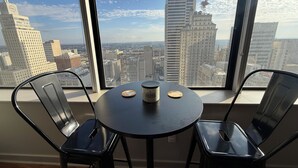 A room with a round table, two chairs, and a view of a cityscape through large windows. - Family-friendly Dallas getaway with rooftop pool, free parking & Texas flair. (Dallas)
