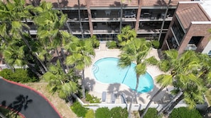 A multi-story hotel with a central swimming pool surrounded by palm trees. - Villa del Sol - #205 (South Padre Island)