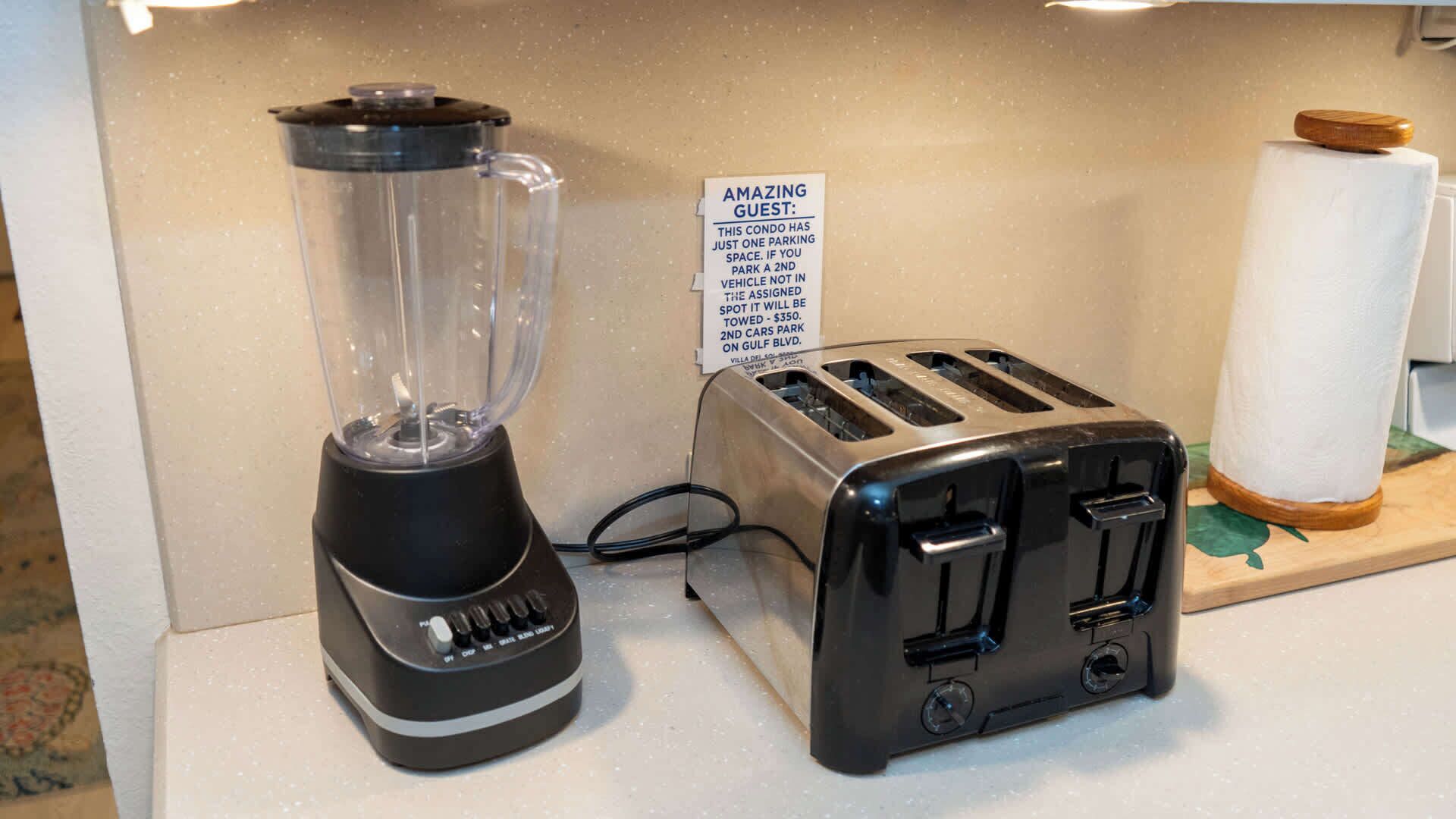 A kitchen with a blender, toaster, and a sign indicating a parking space limit.