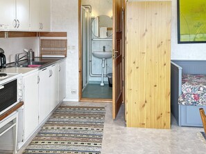 Compact kitchen with stove and adjacent bathroom with sink and mirror.