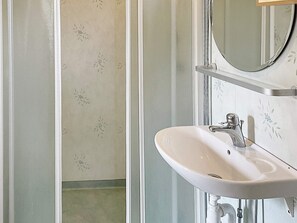 Bathroom features a sink and mirror, surrounded by a floral wallpaper design.