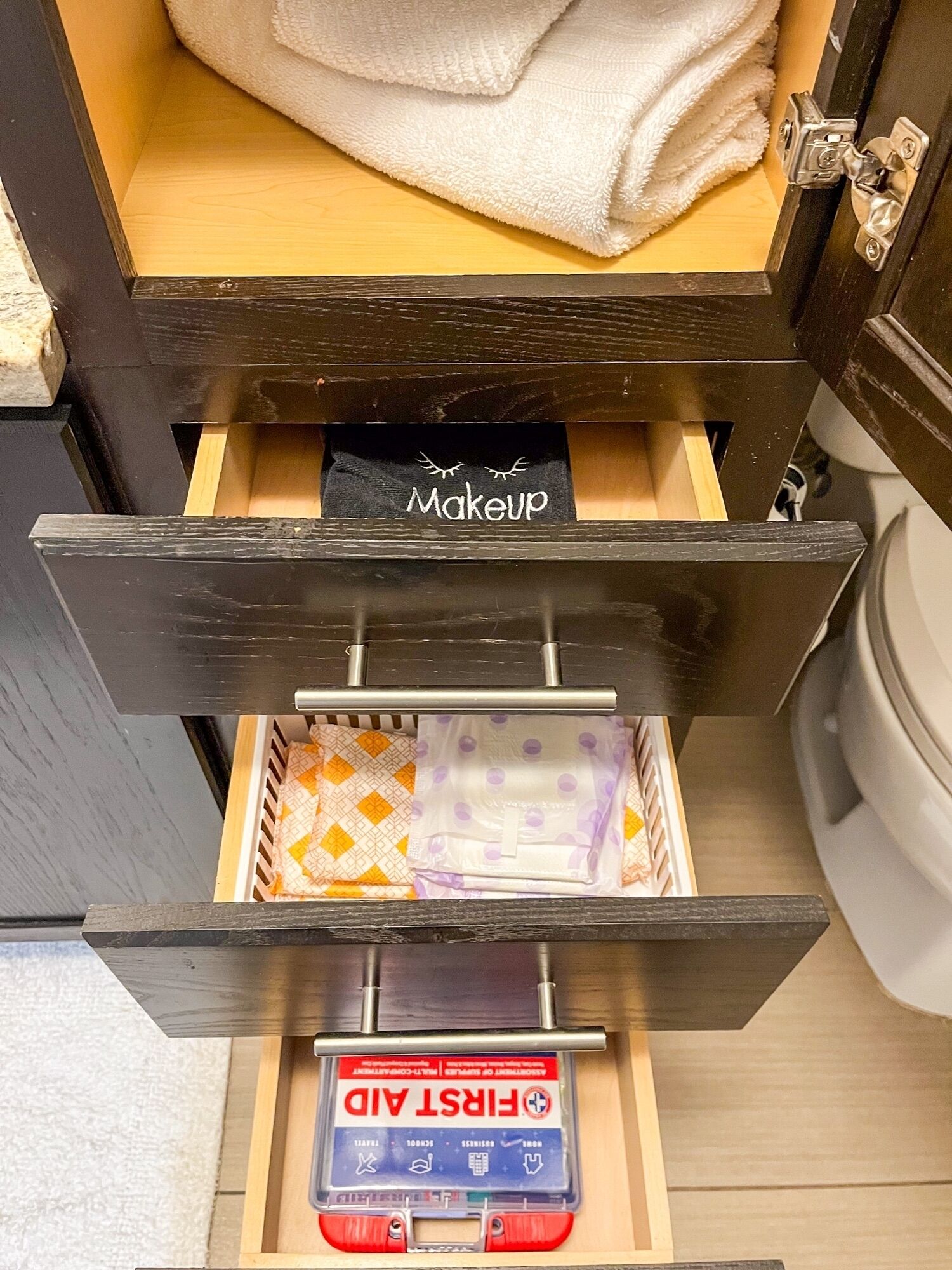 A storage drawer with a makeup bag and a first aid kit.
