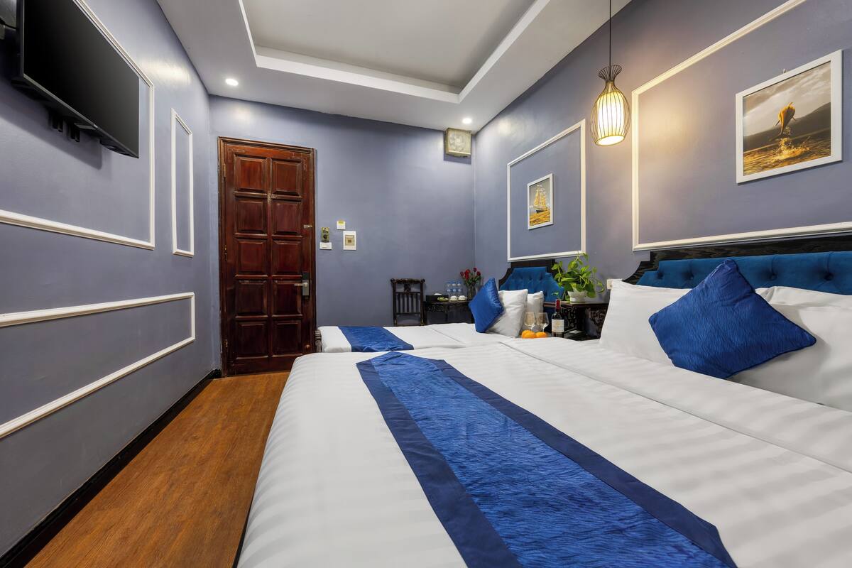 A hotel room with a large bed, a wooden door, a flat-screen TV, and a framed picture on the wall.