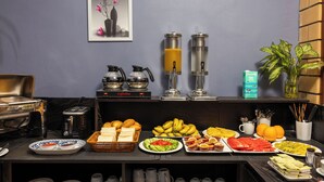 Een ontbijtbuffet met diverse soorten eten, een koffieapparaat en een sapautomaat.