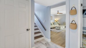 A staircase leading to a living room with a sofa, a lamp, and a ceiling fan. - Luxury Hilton Head Townhome with pool and biking distance to beach (Hilton Head Island)