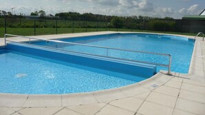 Ein rechteckiger Pool mit einem Metallgeländer, umgeben von einer gefliesten Liegefläche.