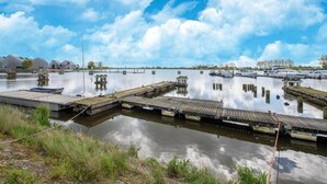 Ein Yachthafen mit anlegenden Booten, ruhigem Gewässer und Industriegebäuden im Hintergrund.