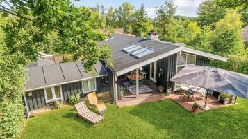 A modern house with a covered patio, a lawn, and a large umbrella.