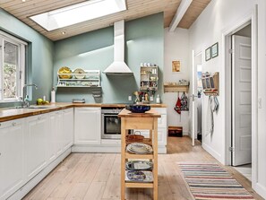 A modern kitchen with white cabinets, a wooden countertop, and a skylight. - 4 Star Holiday Home in Glesborg (Glesborg)
