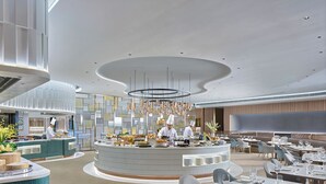 A modern restaurant with a central counter, multiple seating areas, and a contemporary ceiling design. - Hopewell Hotel (Hong Kong)