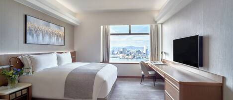 A modern hotel room with a large bed, a desk, a TV, and a city view.