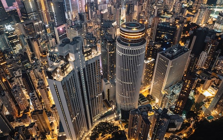 A high-rise building with a circular top, surrounded by other tall buildings in a densely packed urban area.