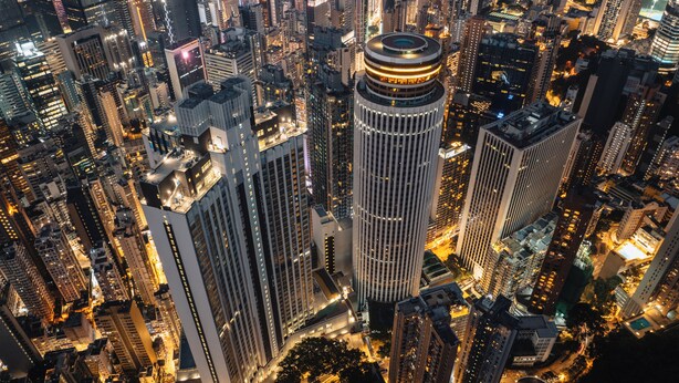 A high-rise building with a circular top, surrounded by other tall buildings in a densely packed urban area. - Hopewell Hotel (Hong Kong)