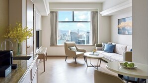 A modern hotel room with a city view, a sofa, a dining table, and a kitchen area. - Hopewell Hotel (Hong Kong)