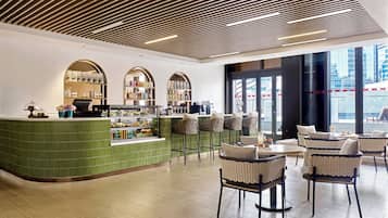 A modern cafe with a green counter, wicker chairs, and a wooden ceiling.