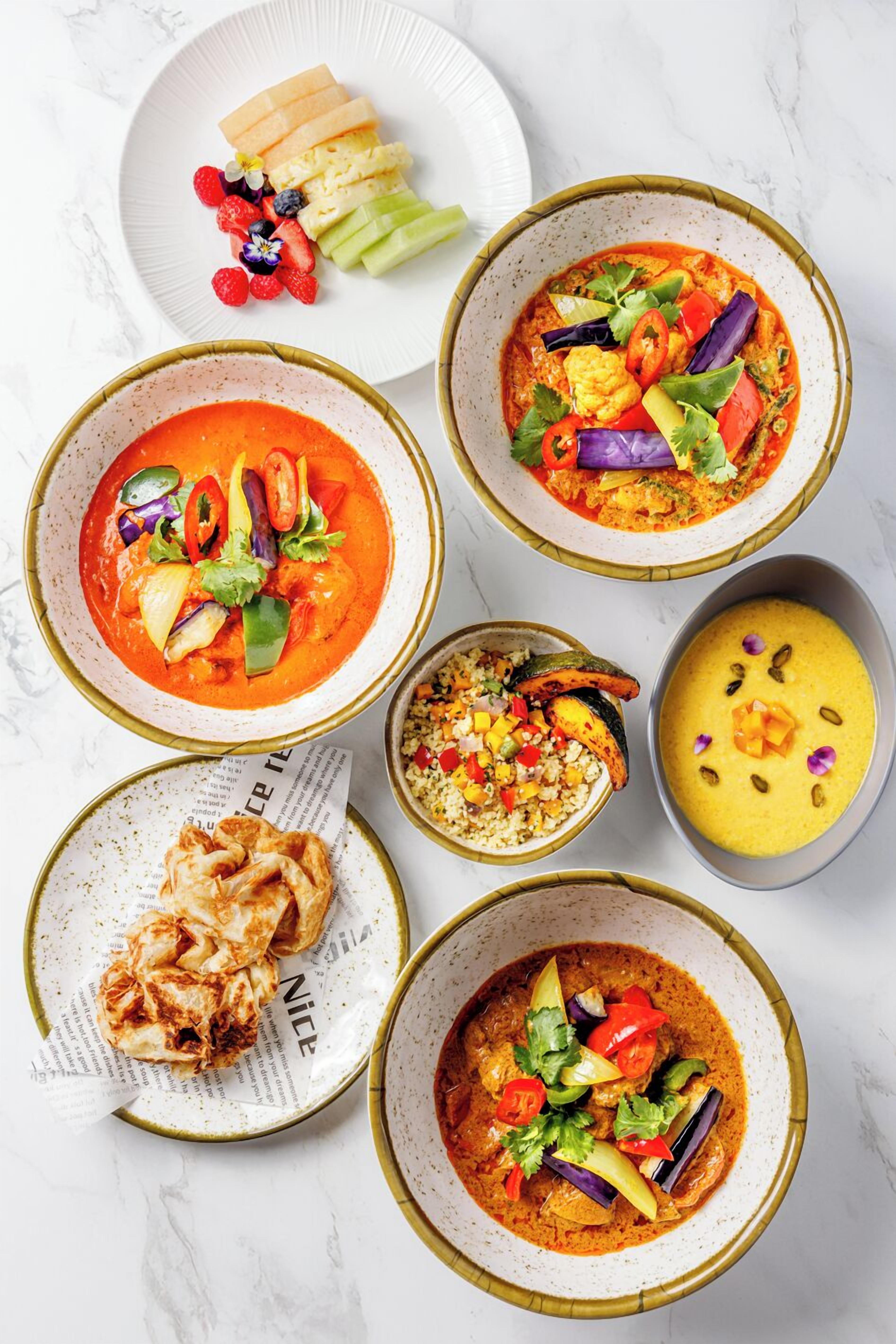 A variety of dishes including a bowl of soup, a plate of fruit, and a bowl of rice.