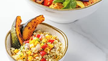 Deux bols de nourriture : l’un contient un plat de curry et des légumes, et l’autre, du couscous et des légumes.