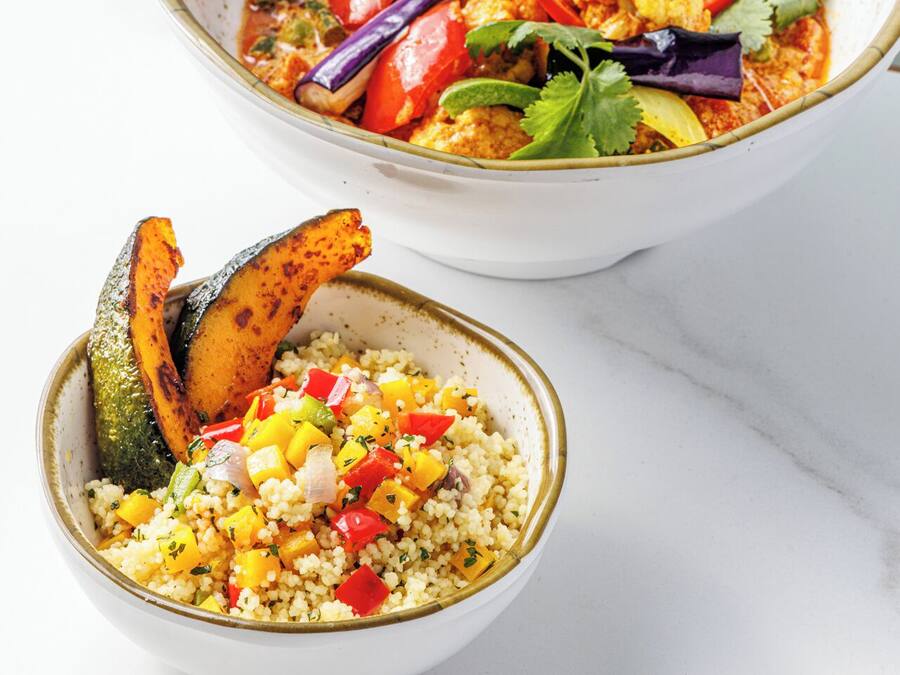 Deux bols de nourriture : l’un contient un plat de curry et des légumes, et l’autre, du couscous et des légumes.