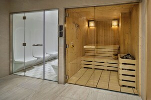 Una sala de sauna con bancos de madera y una puerta de vidrio que da a una zona de duchas.