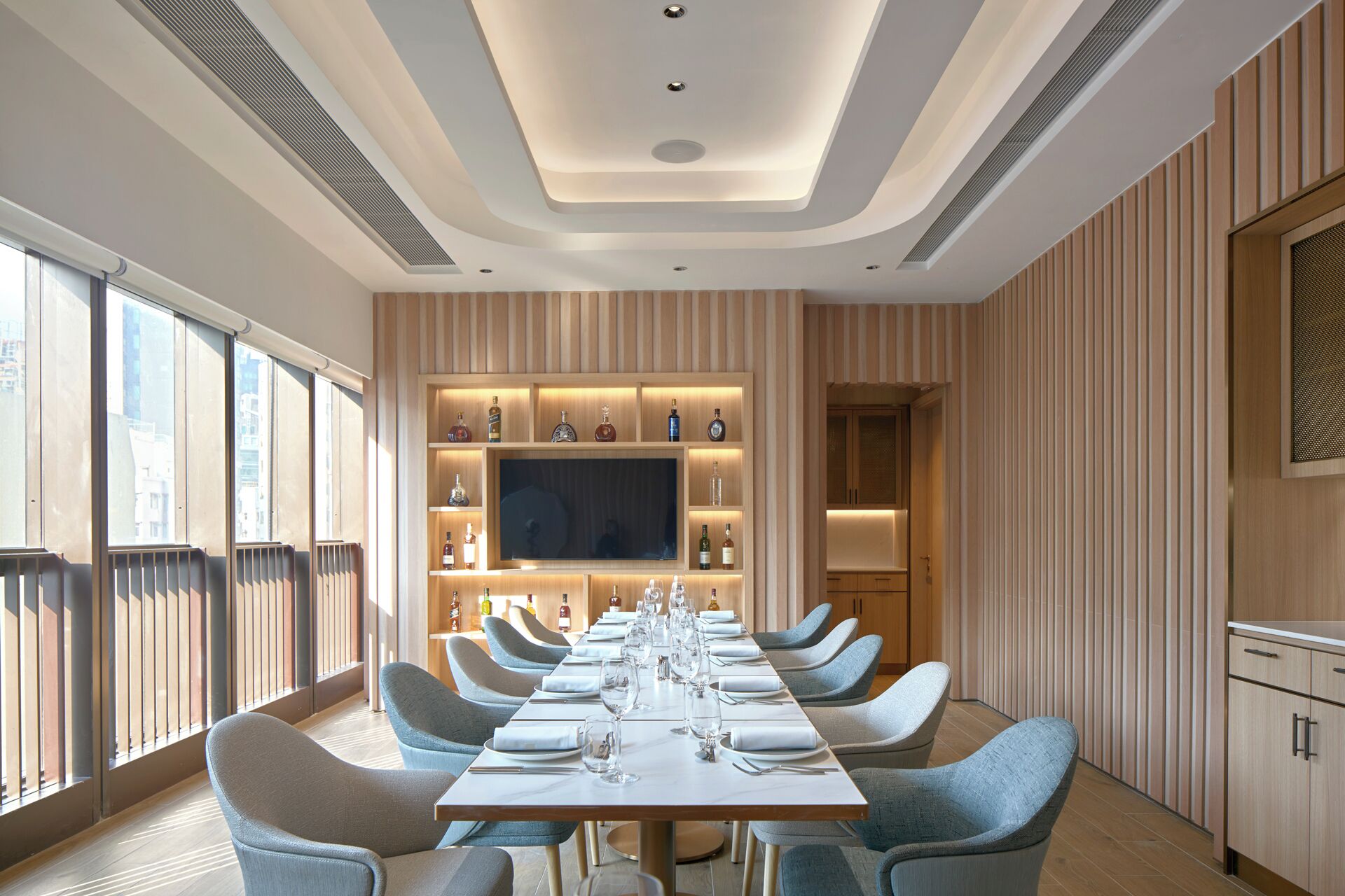 A modern dining area with a long table set for a meal, surrounded by comfortable chairs.