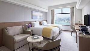 A hotel room with a bed, a sofa, a desk, and a view of a cityscape. - Hopewell Hotel (Hong Kong)