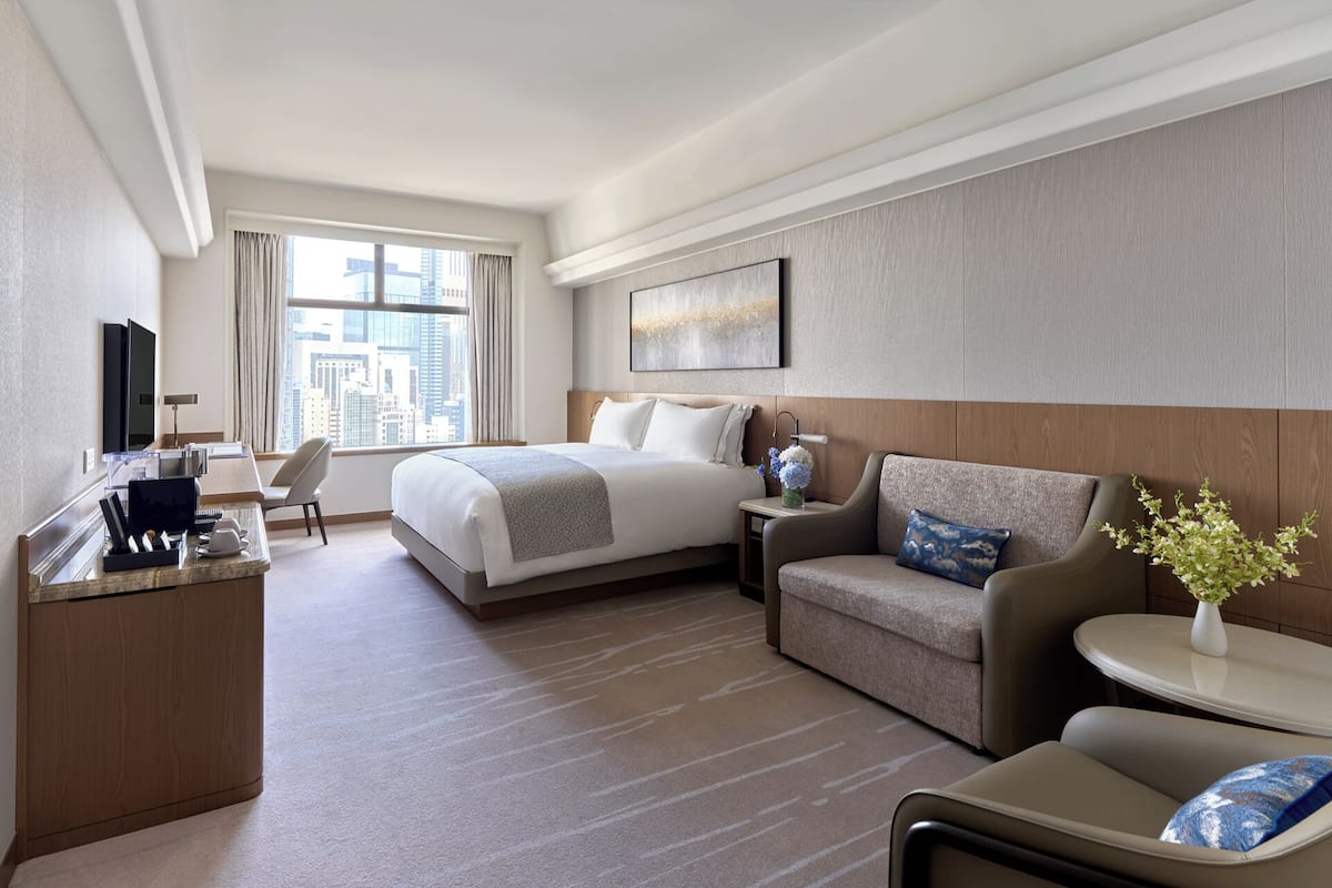 A hotel room with a bed, a desk, a sofa, and a small table.