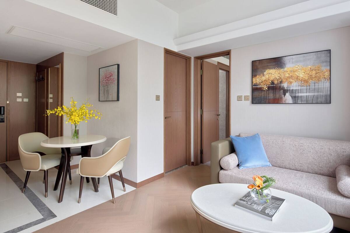 A modern hotel room with a dining area, a sofa, and a coffee table.