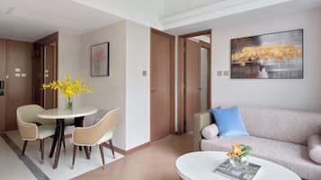 A modern hotel room with a dining area, a sofa, and a coffee table.