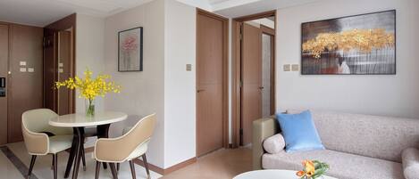 A modern hotel room with a dining area, a sofa, and a coffee table.