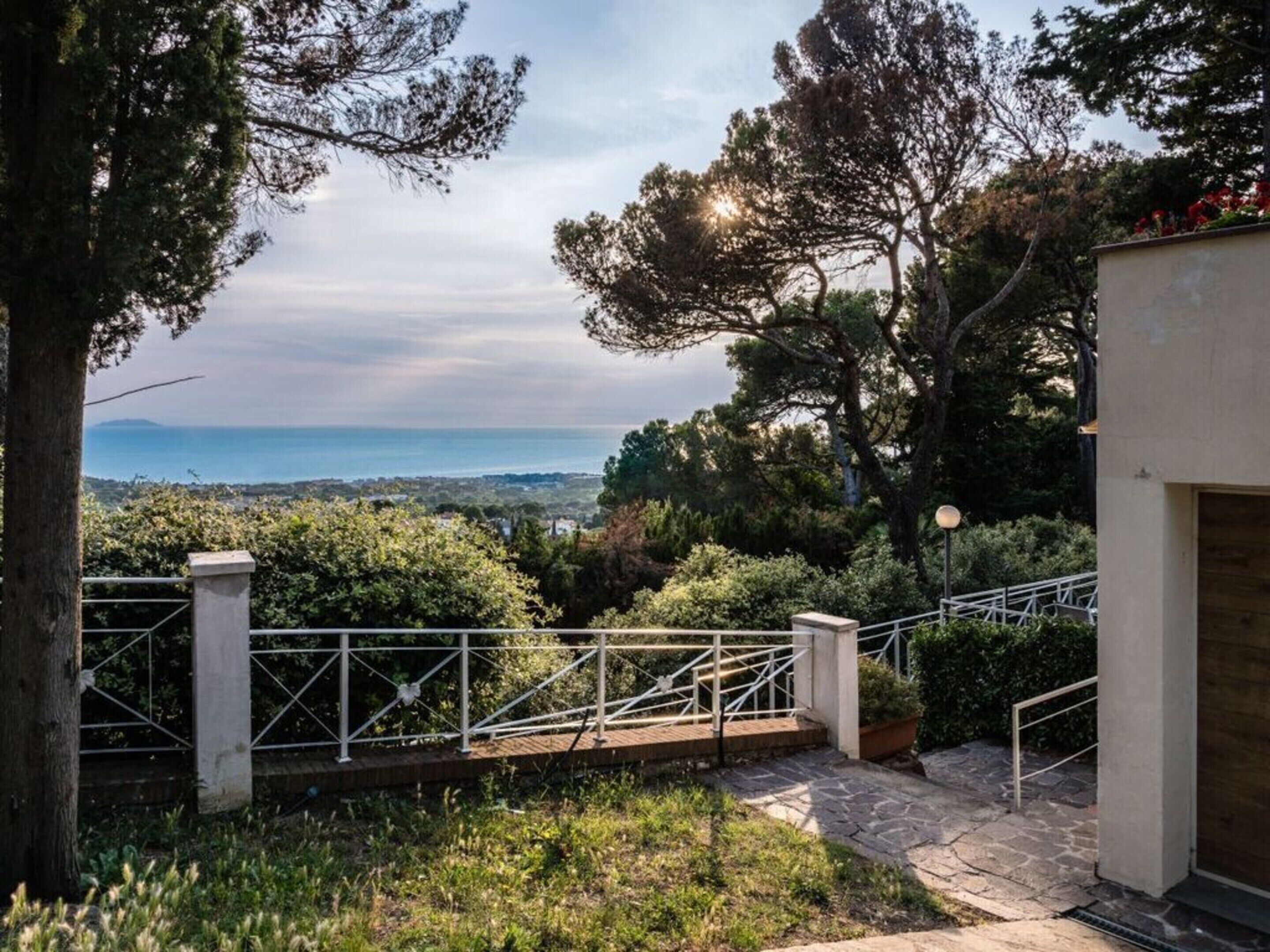 A staircase leading to a terrace with a view of the sea and surrounding greenery.