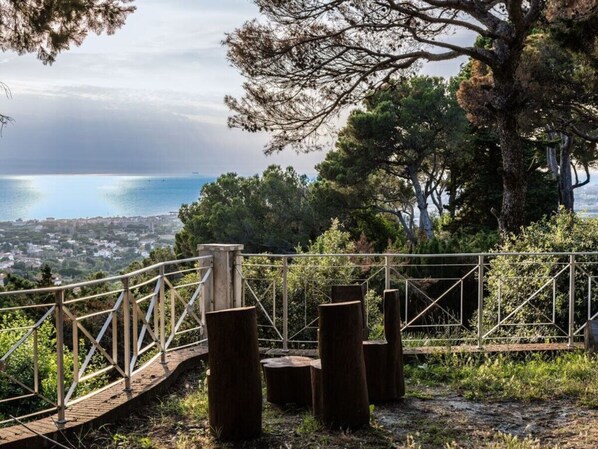 A wooden viewing platform with a metal railing overlooking a coastal town and the sea.