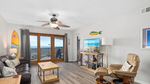 A living room with a sofa, a recliner, a coffee table, a TV, and a surfboard decoration. - La Mirage Condo 311 Beachfront Resort Condominiums with Private Boardwalk (Port Aransas)