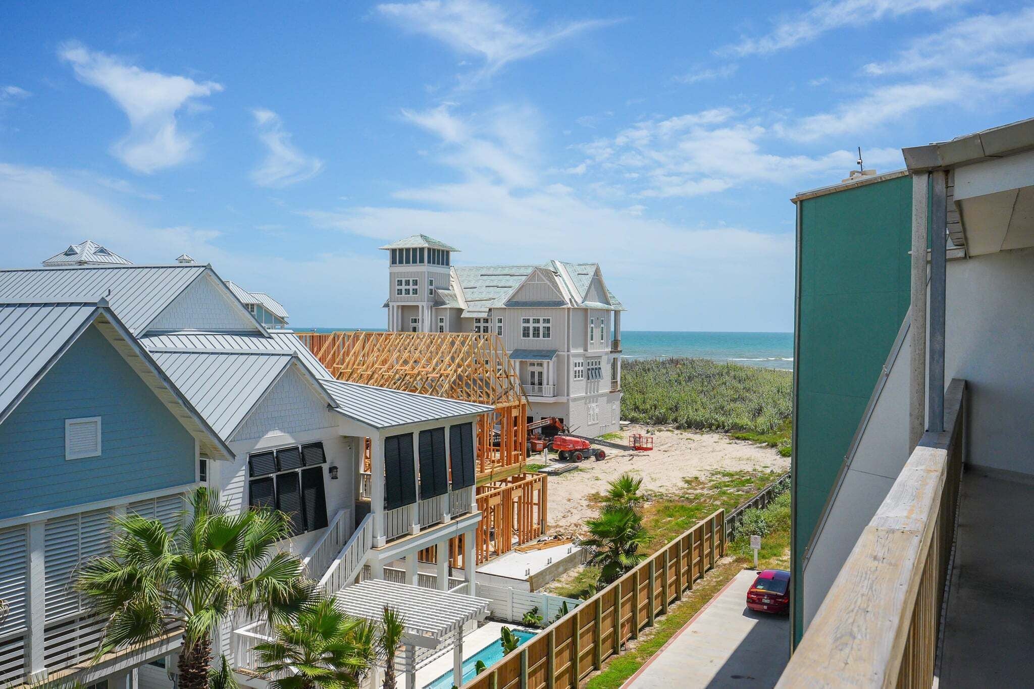 Una zona residencial costera con casas, una playa arenosa y cielo despejado.
