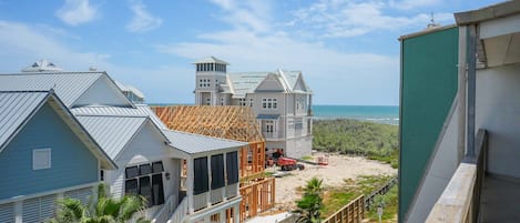 Una zona residencial costera con casas, una playa arenosa y cielo despejado.