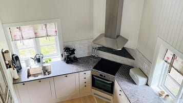 A kitchen with a window, a coffee maker, and a stove.