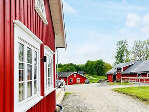 A red building with multiple windows and a gravel driveway.