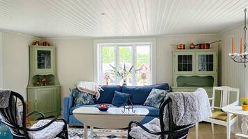 A cozy living room with a blue sofa, a white coffee table, and a patterned rug.