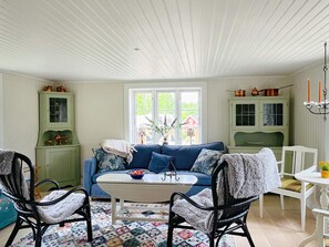 A cozy living room with a blue sofa, a white coffee table, and a patterned rug. - 4 Person Holiday Home in Allingsas, Sverige (Alingsas)