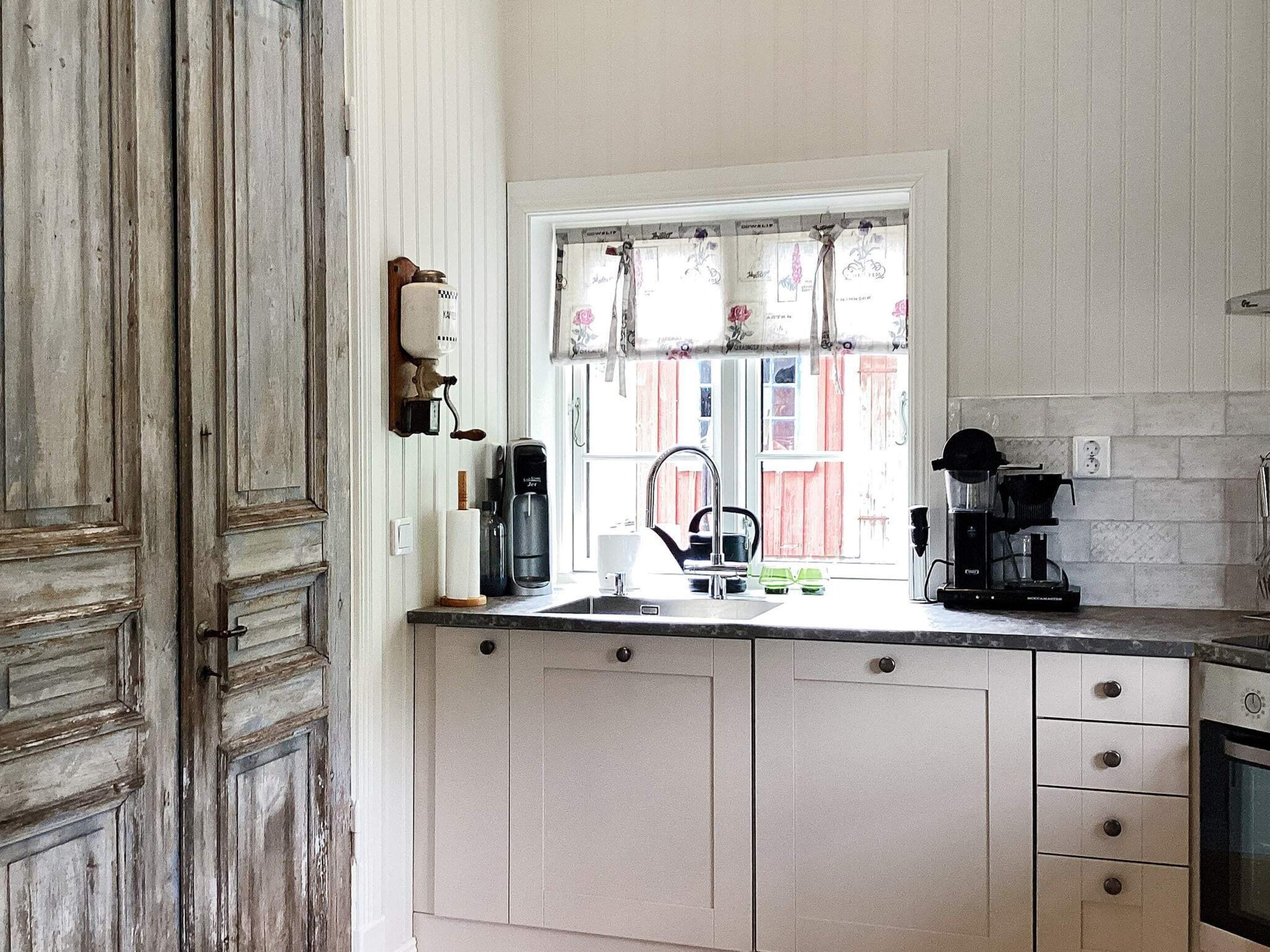 Ett kök med ett fönster, en kaffebryggare och en diskho.