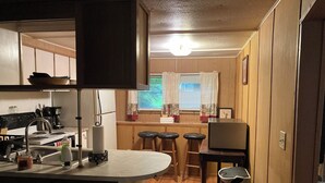 Una cocina compacta con estufa, lavamanos y taburetes de bar.