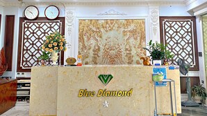 A reception desk with a marble top, a ceiling fan, and decorative wall panels. - Blue Diamond Hotel (Hong Gai)