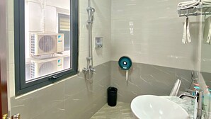 A modern bathroom with a large window, a shower, a sink, and a towel rack. - Blue Diamond Hotel (Hong Gai)