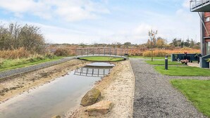 A modern building with a gravel pathway leading to a small bridge over a water feature. - 4 Star Holiday Home in Bogense (Bogense)