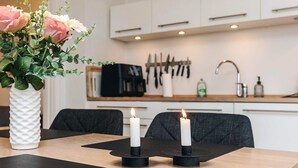 A modern kitchen with white cabinets, a coffee machine, and a sink. There are two candles on the table. - 4 Star Holiday Home in Bogense (Bogense)