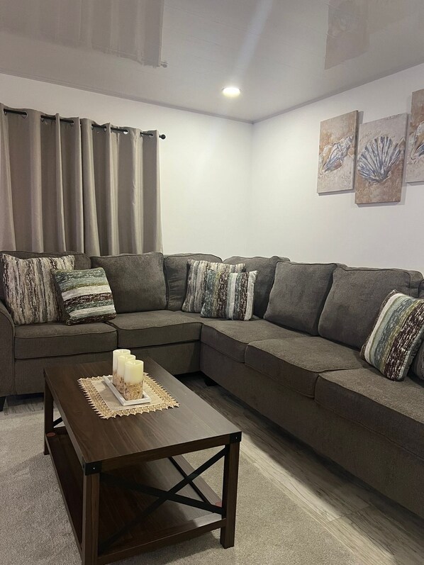 A modern living room with a sectional sofa, a wooden coffee table, and decorative pillows. - Crusoe Escape Villa (Crown Point)