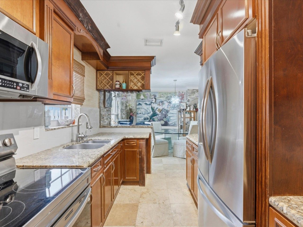 A kitchen with wooden cabinets, stainless steel appliances, and a marble countertop.