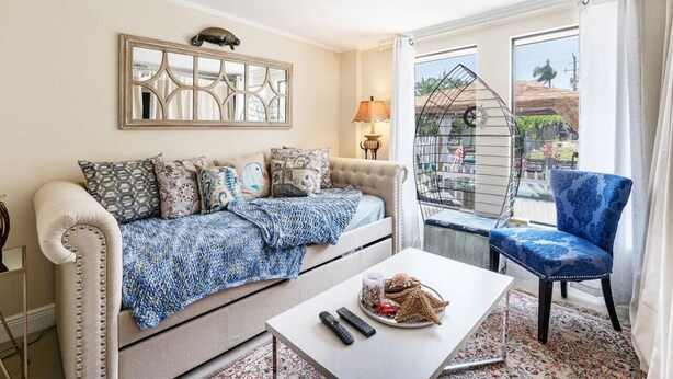 Un salon comprenant un canapé, une table basse et un fauteuil. Il y a un balcon avec une balustrade et une vue sur l’extérieur.